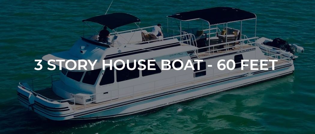 Three-story 60-foot white houseboat with upper sun decks and black canvas canopies cruising on turquoise coastal waters
