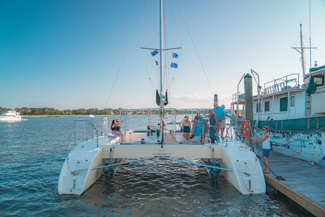 Sunlit catamaran docked at a Hilton Head, SC marina with guests boarding for a coastal sightseeing cruise