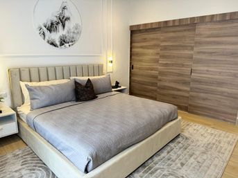 Contemporary bedroom with upholstered king bed dressed in gray quilt and pillows, round monochrome wall art, wood sliding closet doors and light wood floors