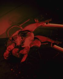 Red-lit nightclub scene of a burlesque pole dancer in sparkly lingerie and high heels, inverted on a pole under dramatic neon lighting.