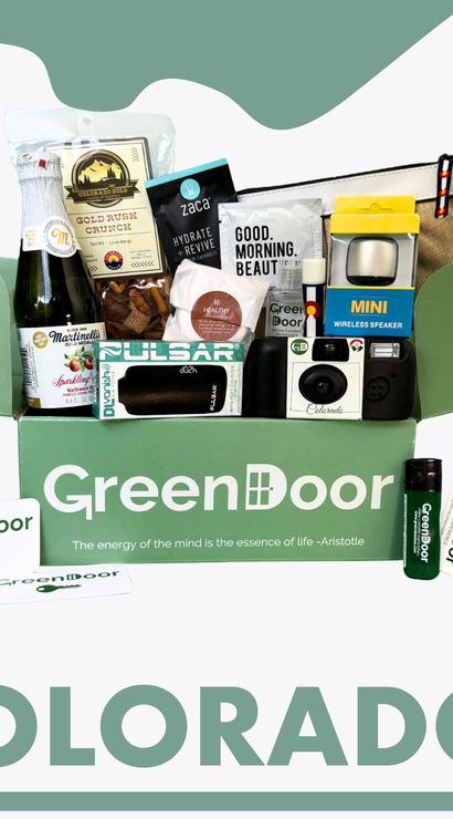Curated Colorado gift box in green, filled with local snacks, sparkling cider, mini wireless speaker, camera, lip balm and travel pouch.