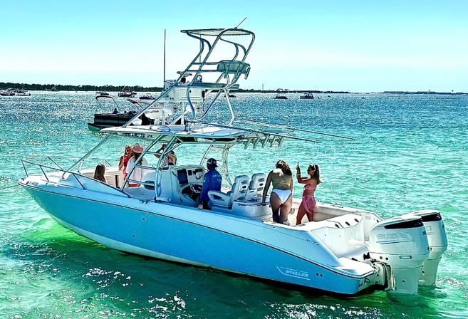 Group of friends on a white center-console powerboat with twin outboard engines enjoying clear turquoise coastal waters under a sunny blue sky