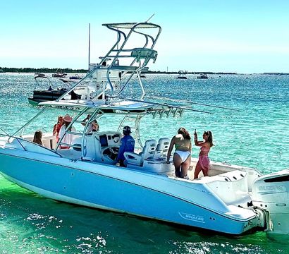 Group of friends on a white center-console powerboat with twin outboard engines enjoying clear turquoise coastal waters under a sunny blue sky