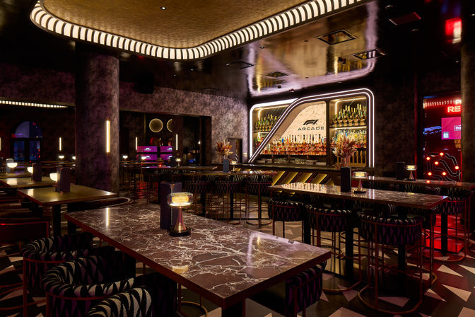 Upscale neon-lit bar and lounge interior with marble tables, LED ceiling trim, stocked back bar and arcade-style gaming machines
