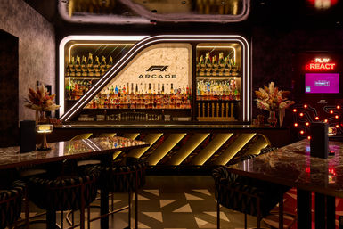Neon-lit luxury bar interior with backlit marble bottle display, rows of spirits and champagne, marble tables, floral centerpieces and a glowing arcade gaming kiosk.
