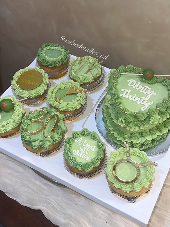 Mint-green buttercream cupcakes and matching mini layered cake on a white board — martini-themed 30th birthday desserts with gold accents, olive picks, piped “Dirty Thirty” and “A tini bit older” lettering.