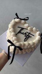Mini heart-shaped buttercream cake with piped ruffle border, black script “thirty” topper and black satin bows, presented on a white box — chic 30th birthday mini cake