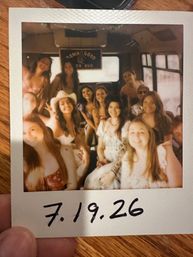 Polaroid snapshot of a smiling group of friends on a party bus, warm vintage tones, summer outfits and a cowboy hat, handwritten date “7.19.26” at the bottom.