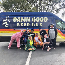 Smiling group in animal onesies and security shirts posing in front of a colorful beer tour van in a parking lot — playful costume party vibe