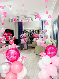 Barbie-themed 6th birthday party in a living room with pink, white and silver balloon columns, hanging heart and star cutouts, a large silver '6' balloon and 'Happy Birthday' foil letter balloons