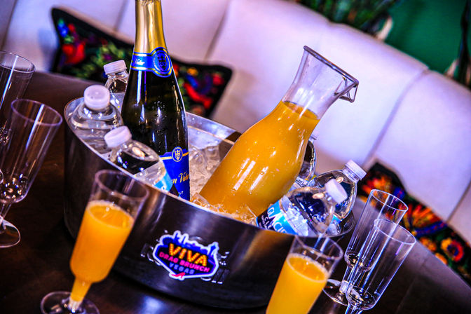 Brunch setup: ice bucket with chilled champagne and water bottles, a carafe of orange juice and champagne flutes ready for mimosas.