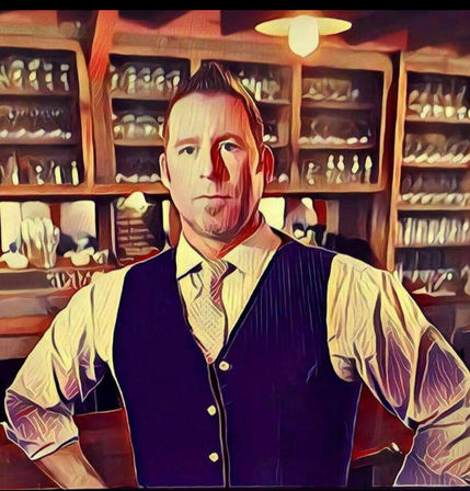 Stylized portrait of a bartender in a vest and tie standing confidently in front of wooden shelves filled with glassware in a cozy cocktail bar