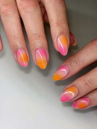 Close-up of glossy almond-shaped ombre nails in bright pink and orange gradient — trendy summer gel manicure, salon-style nail art on hands.