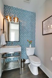 Nashville powder room with blue geometric tile accent wall, chrome-framed sink and mirror, white toilet and tulips in a vase