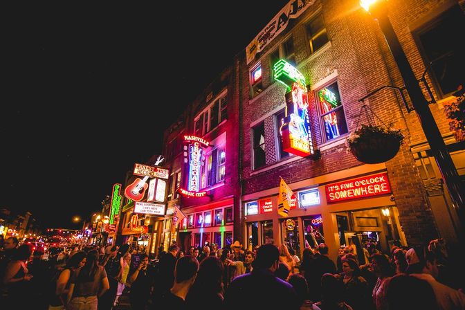 Crowded Nashville nightlife on a neon-lit music street with bars, bright signs and people enjoying live music at night