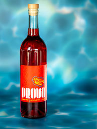 Ruby-red aperitif wine bottle with wooden cork and bright red label, staged on a turquoise pool-like background for a summery cocktail vibe.