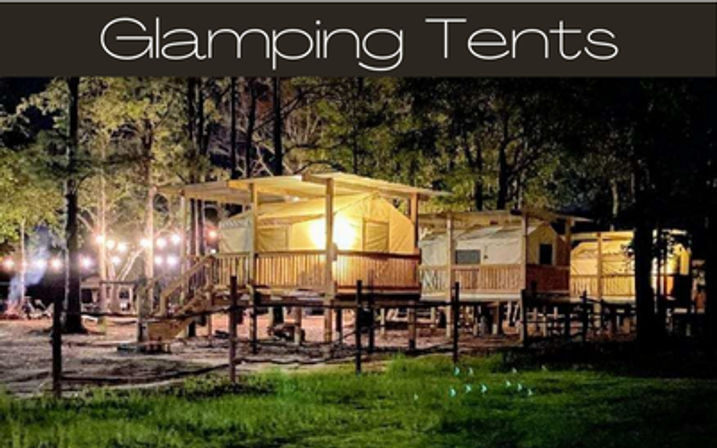 Warmly lit glamping tents on raised wooden decks in a wooded campsite at night, with string lights and porches for luxury camping.