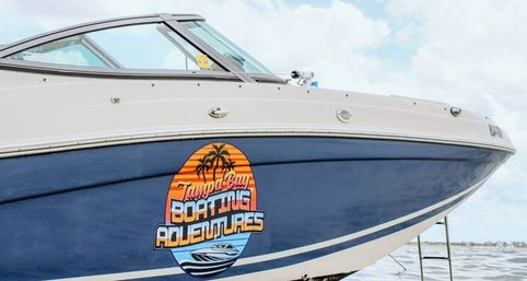 Motorboat docked in Tampa Bay with blue-and-white hull featuring a colorful tropical sunset logo with palm trees and speedboat graphic